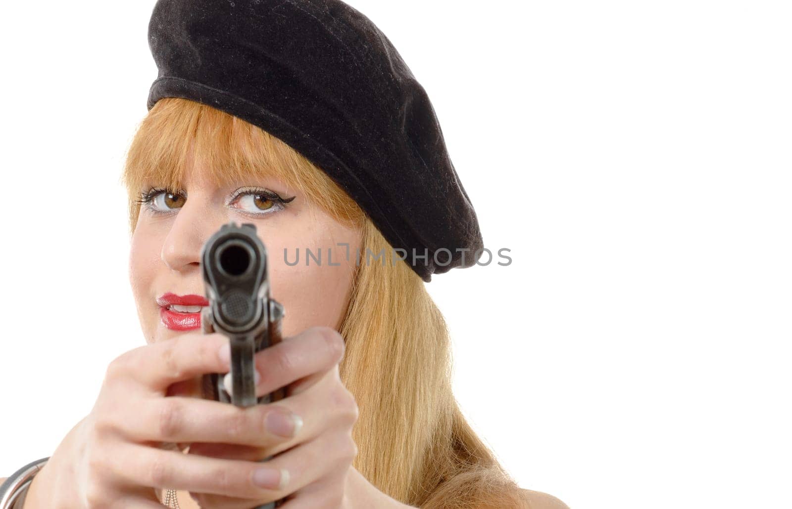 A woman with a gun is wearing a black hat. She is holding the gun up to her face