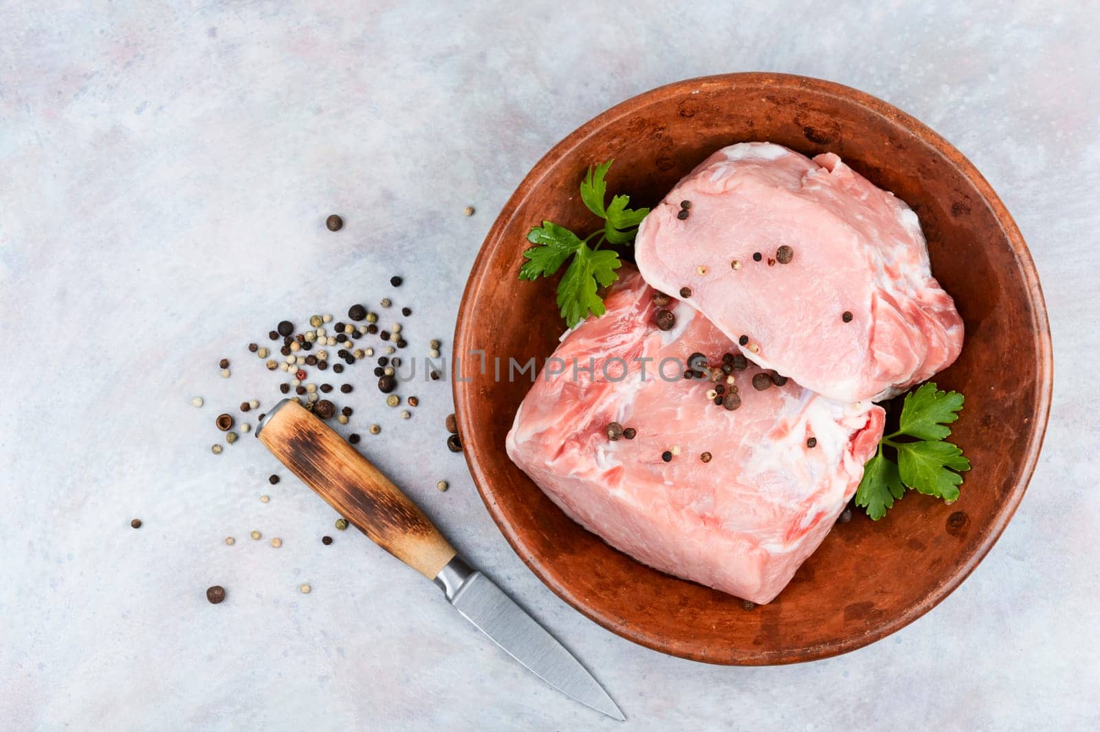 Slices of raw pork meat and vegetables on rustic wooden background.