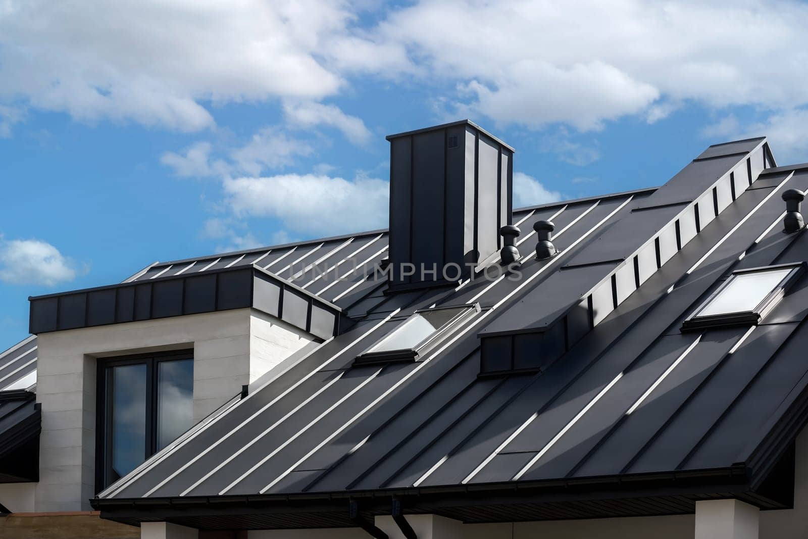 Close-up house retro roof panel with standing seam and fasteners. Classic style black metal panel with rebate joint. Modern galvanized steel roofing sheet with ribs. Falz roofing. Building's covering