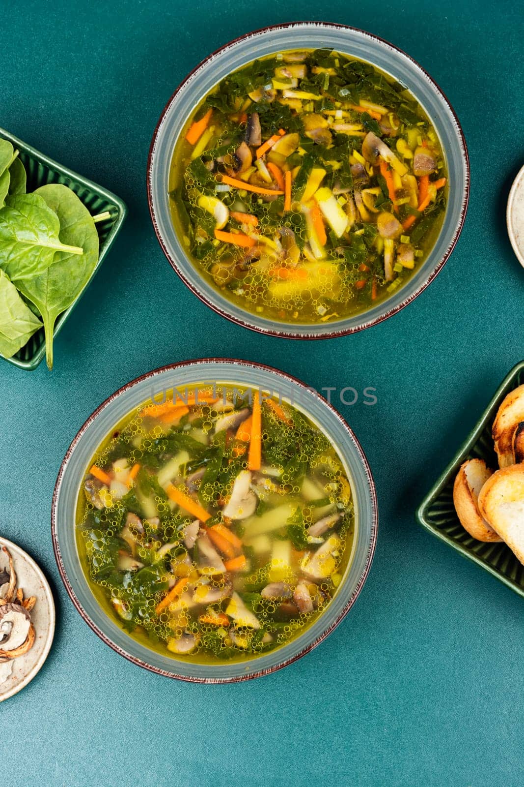 Fresh vegetarian soup filled with mushrooms, spinach with croutons on a table. Top view.