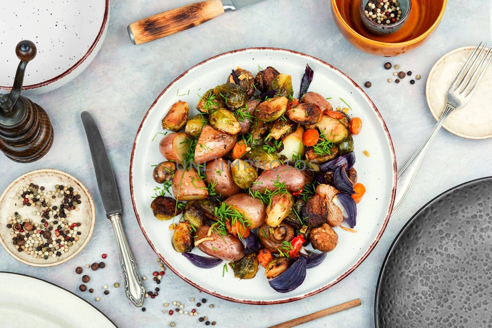Roasted baked mushrooms, Brussels sprouts, and potatoes, garnished with onion in the oven dish. Free space for your text.