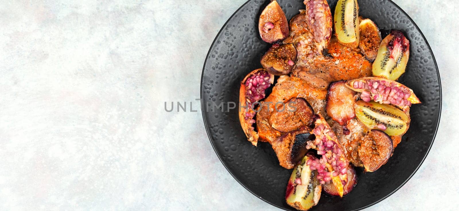 Meat pork steaks roasted with figs, kiwi and pomegranate. Free space for your text.