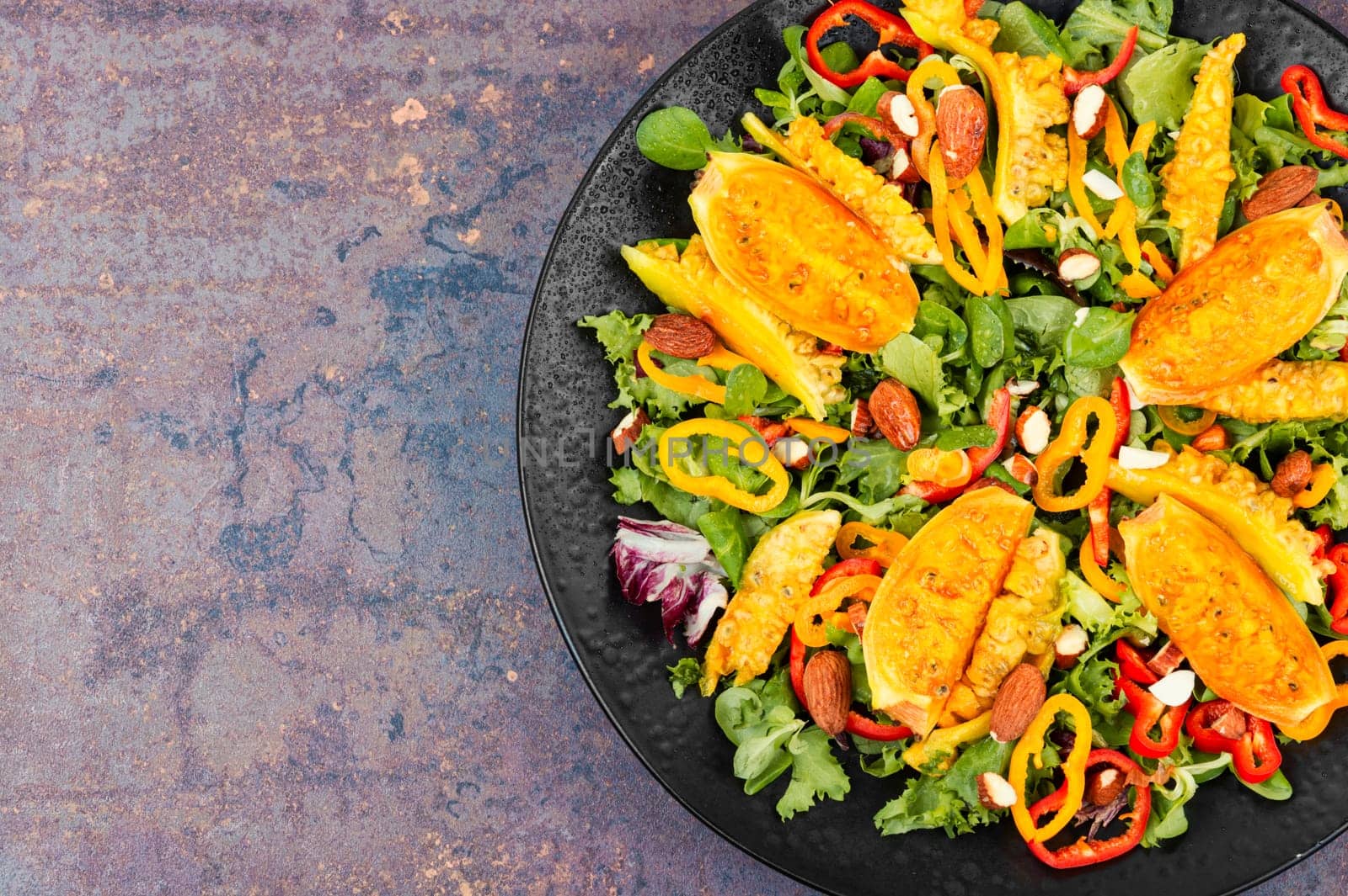 Cactus salad with sliced opuntia or prickly pear, peppers, almonds and fresh herbs, served in plate. Flat lay
