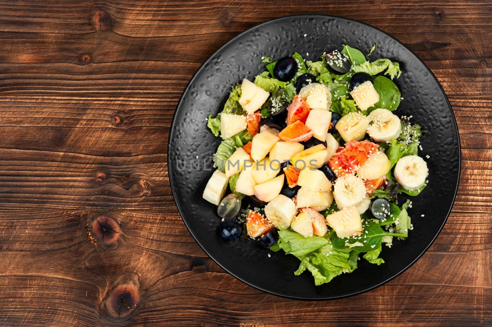Fruit salad of red orange, apple, banana and lettuce. Healthy eating.