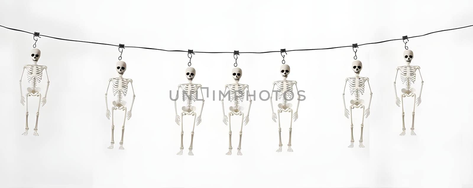 A string of small skeleton decorations hangs against a plain backdrop, adding a playful touch for Halloween festivities. These skeletons are evenly spaced, creating a spooky yet fun atmosphere.