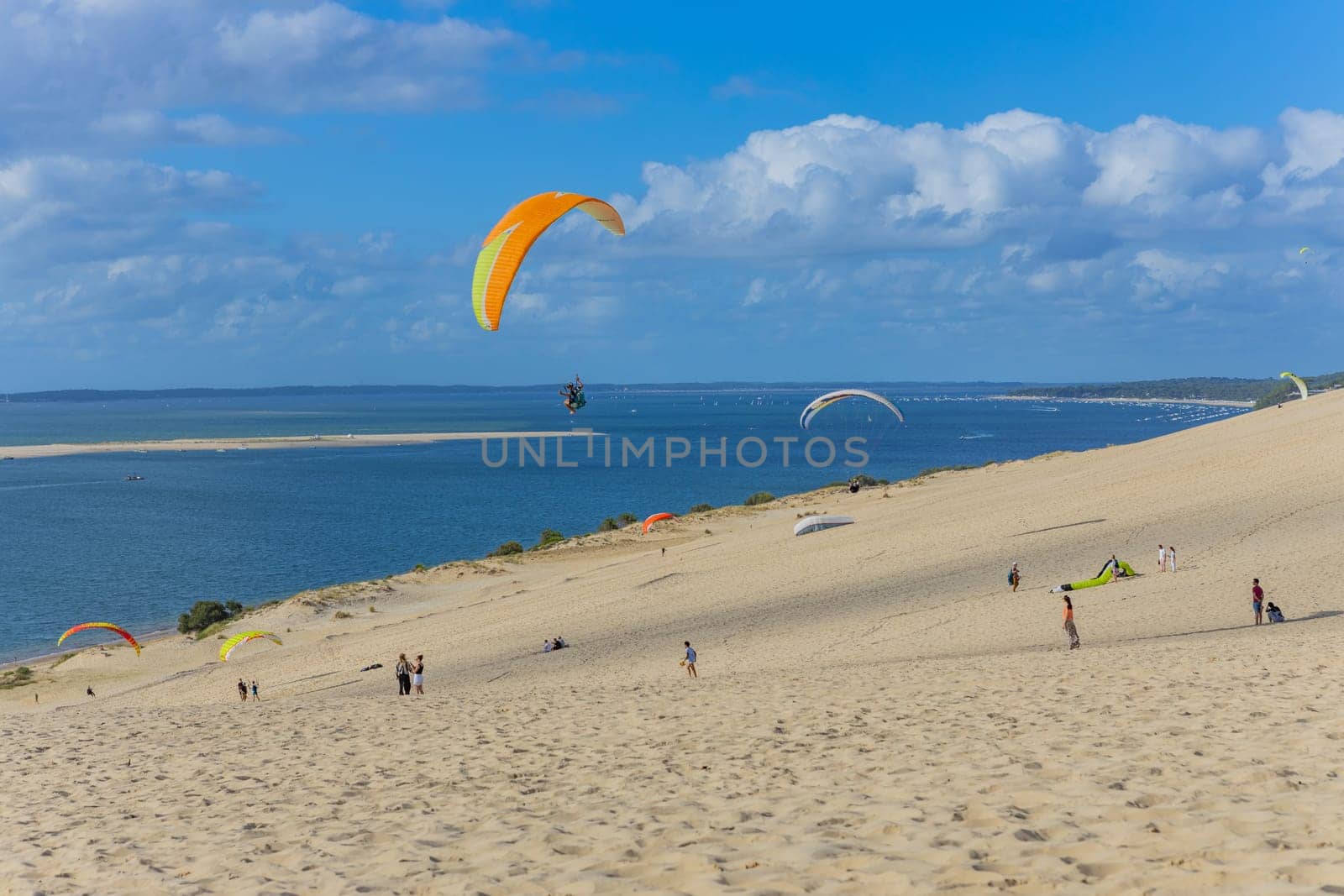 Dune of Pilat, France - August 14, 2024: People paragliding at the Great Dune of Pilat, Arcachon Basin, Nouvelle Aquitaine, France.
