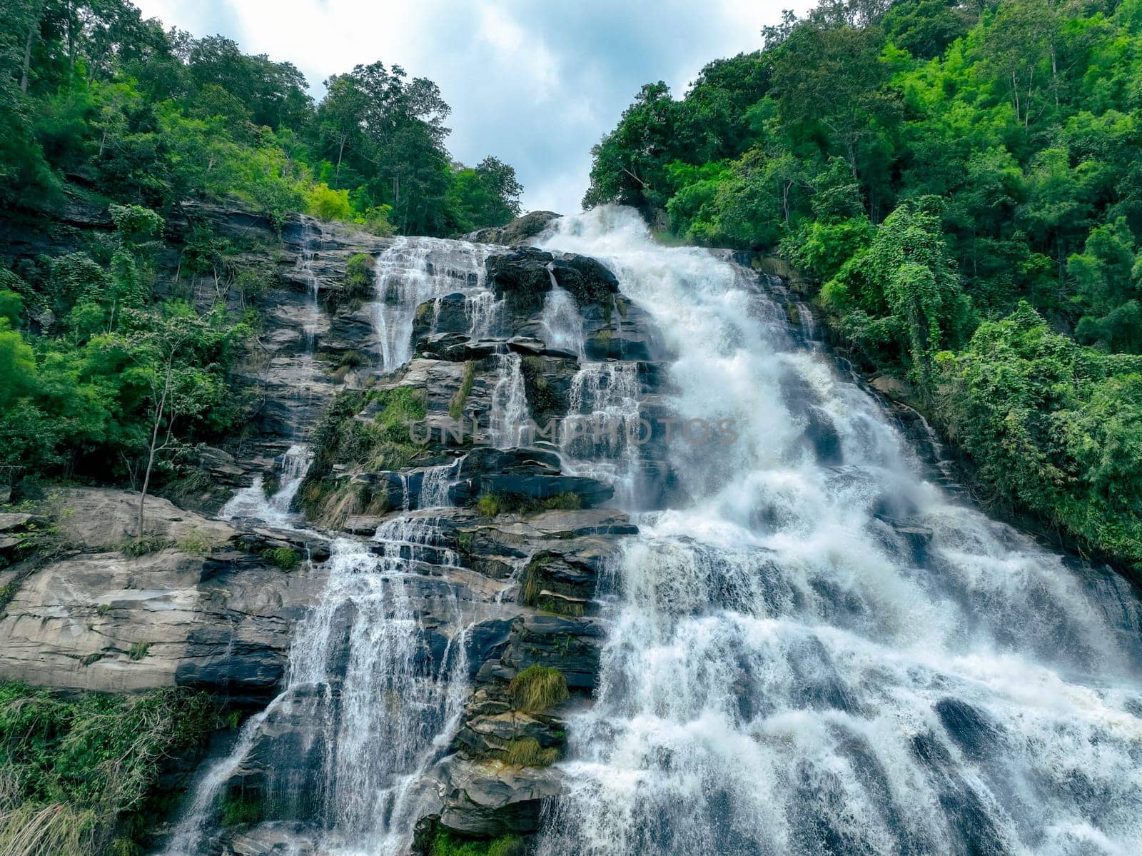 Aerial view of a waterfall in a lush tropical green forest in Doi Inthanon National Park, Chiang Mai, Thailand. This nature landscape showcases water sustainability and scenic travel destinations.