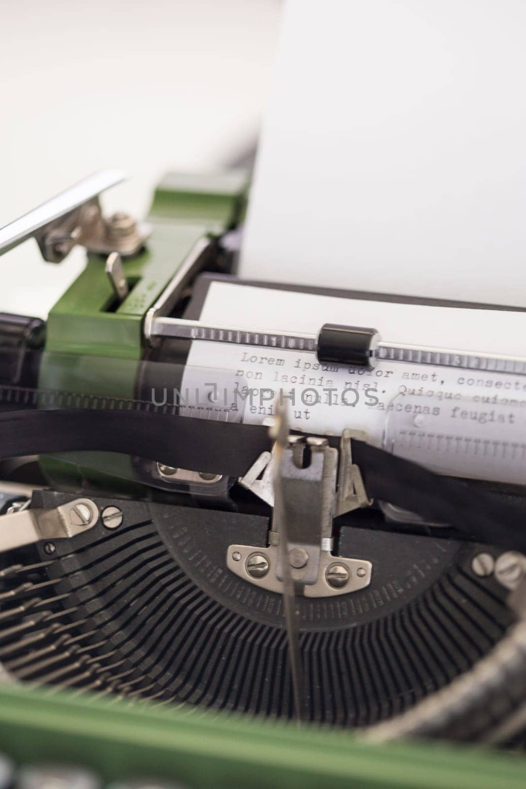 Vintage green typewriter machine with a sheet of paper and generic text typed, closeup photo