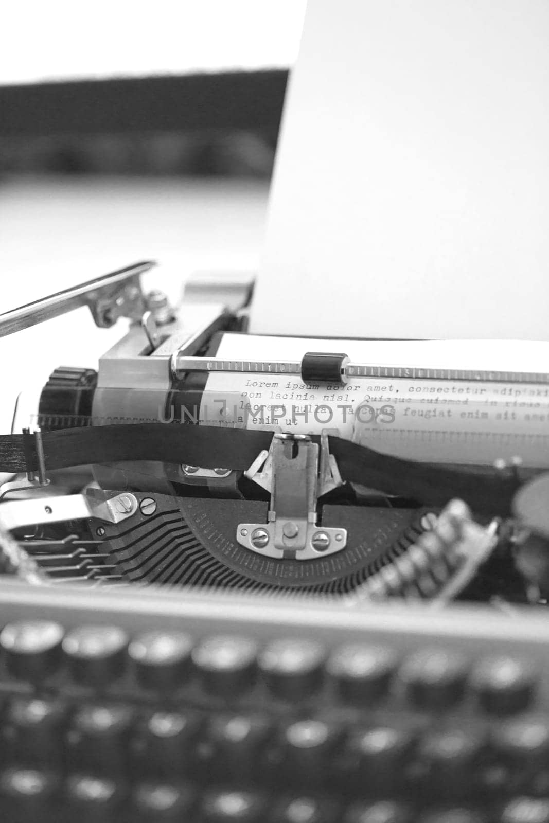 Vintage Typewriter machine with a sheet of paper and generic text typed, closeup black and white photo