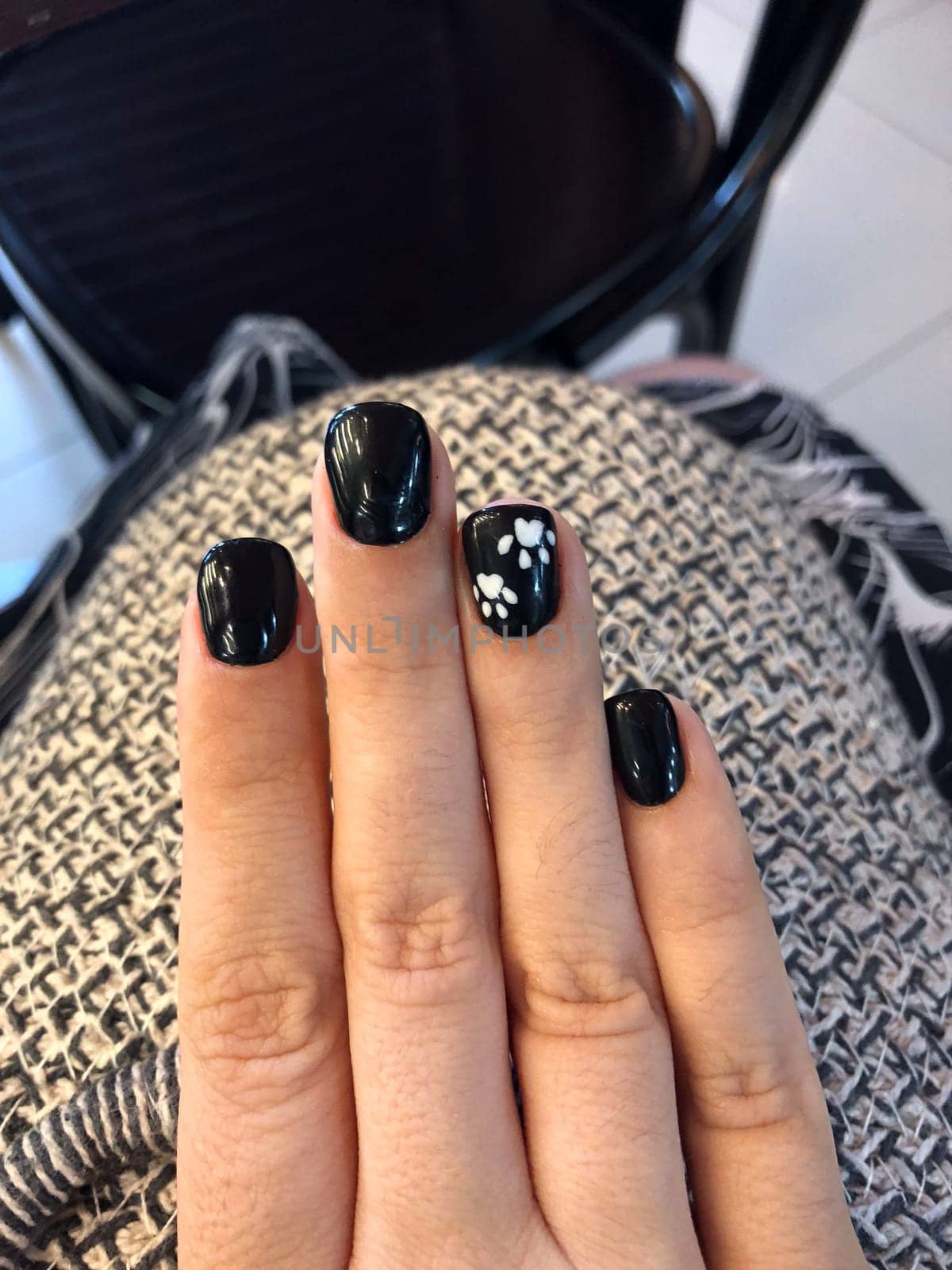 Close-up of a hand with black nail polish and white paw print nail art