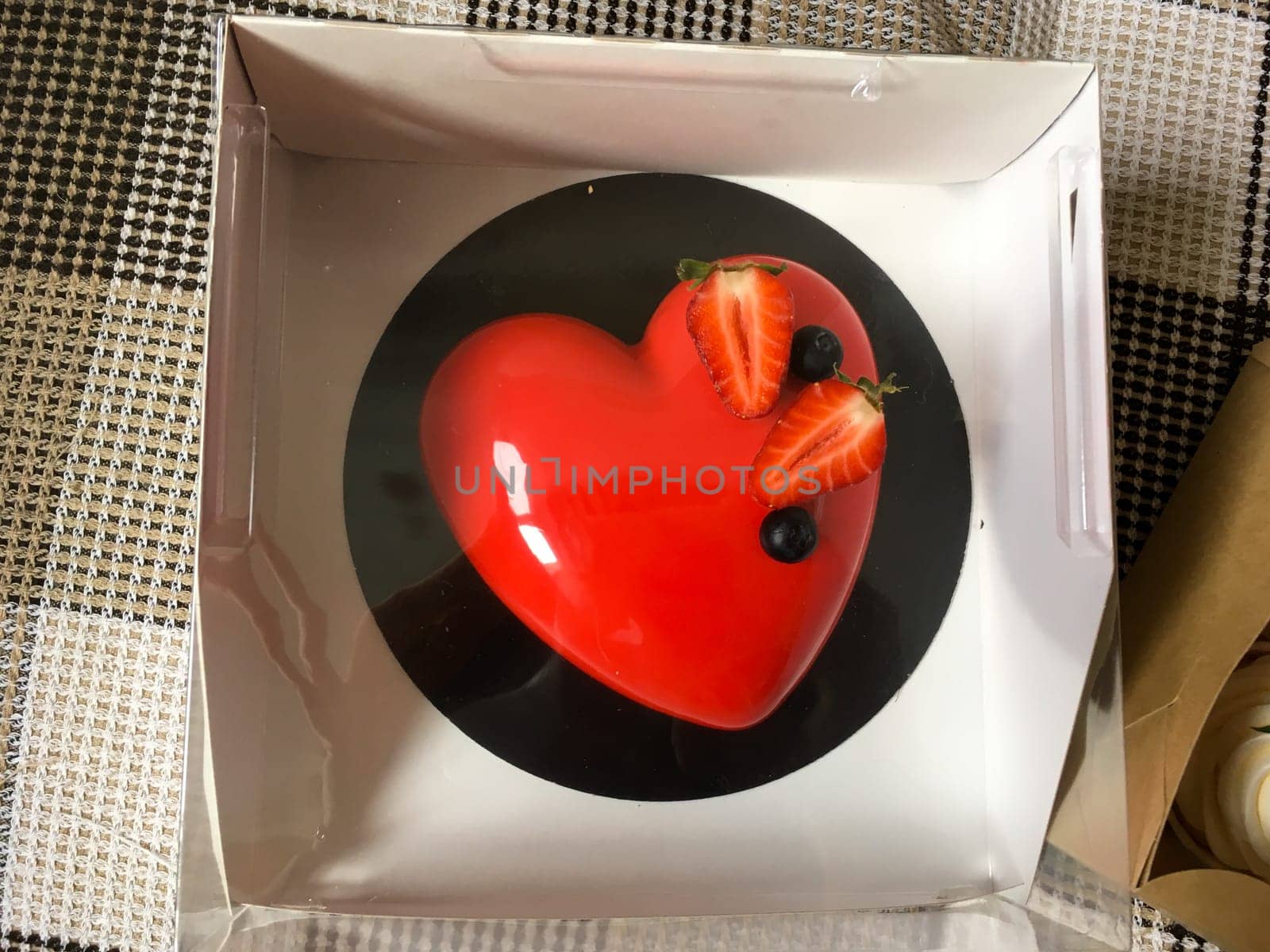 Red cake with strawberries in the shape of a heart top view. St. Valentine's Day sweets and gift.