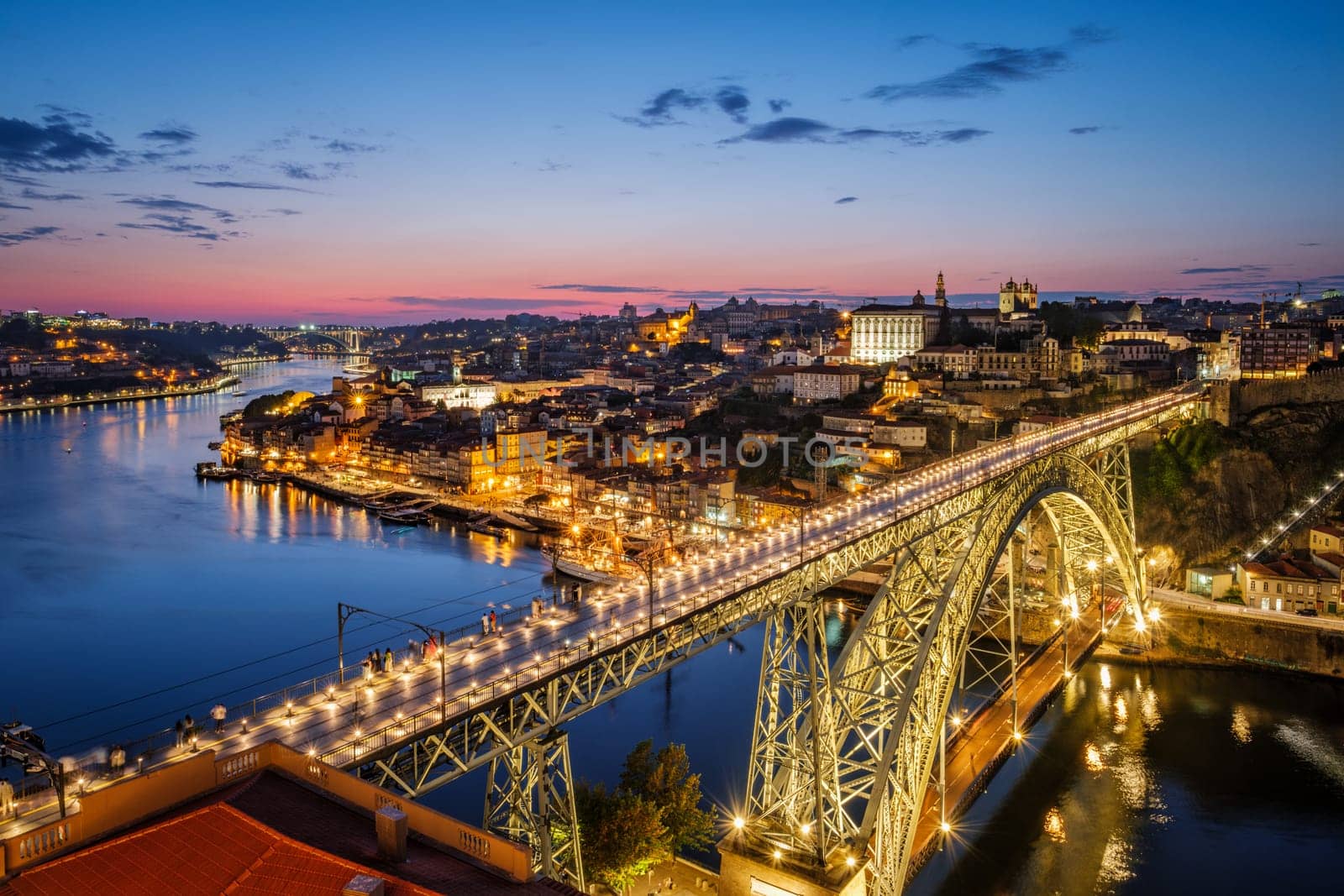View of illuminated Porto city and Douro river and Dom Luis bridge I from famous tourist viewpoint Miradouro da Serra do Pilar in evening twilight. Porto, Vila Nova de Gaia, Portugal