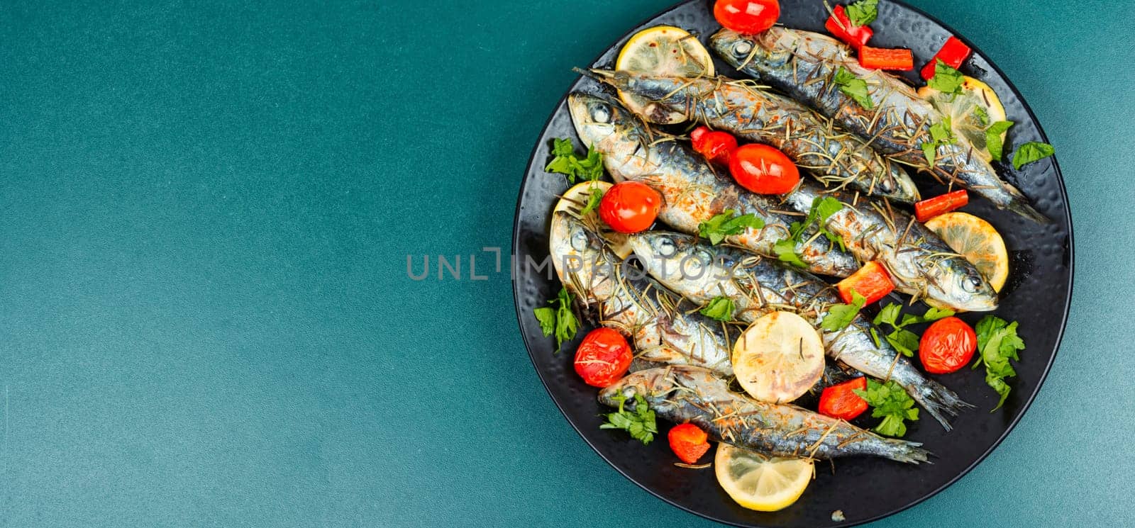 Oven baked italian fish sardoncini or sardines, with tomatoes, lemon and rosemary.