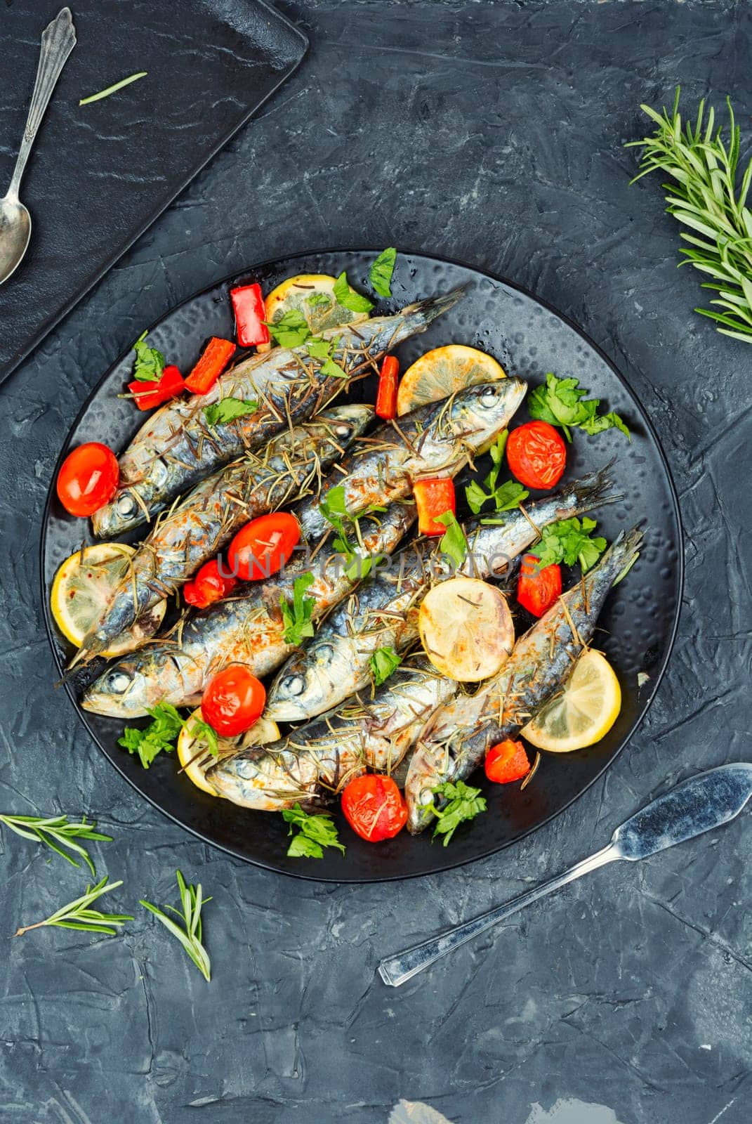 Oven baked italian fish sardoncini or sardines, with tomatoes, lemon and rosemary.