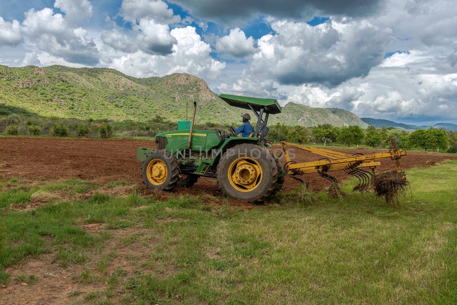 Farmer with green tractor prepares field for sowing, Otavi, Namibia