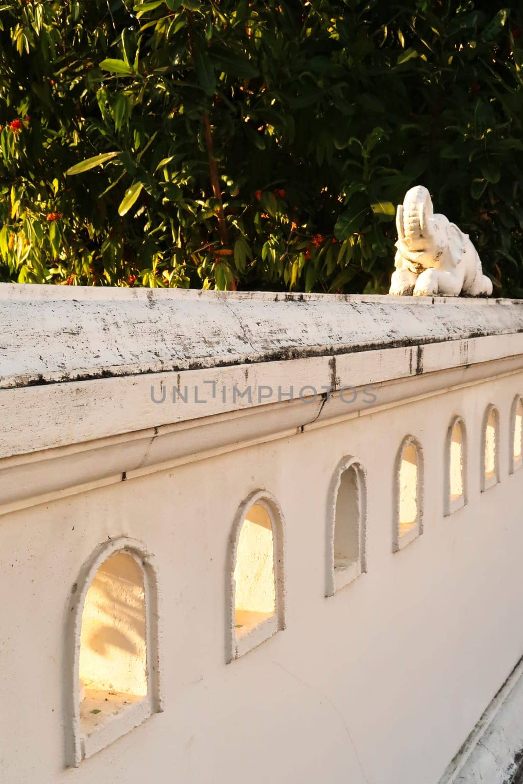 Small decorative elephant sculpture on a white wall next to a park at golden hour, Chiang Mai, Thailand 2023