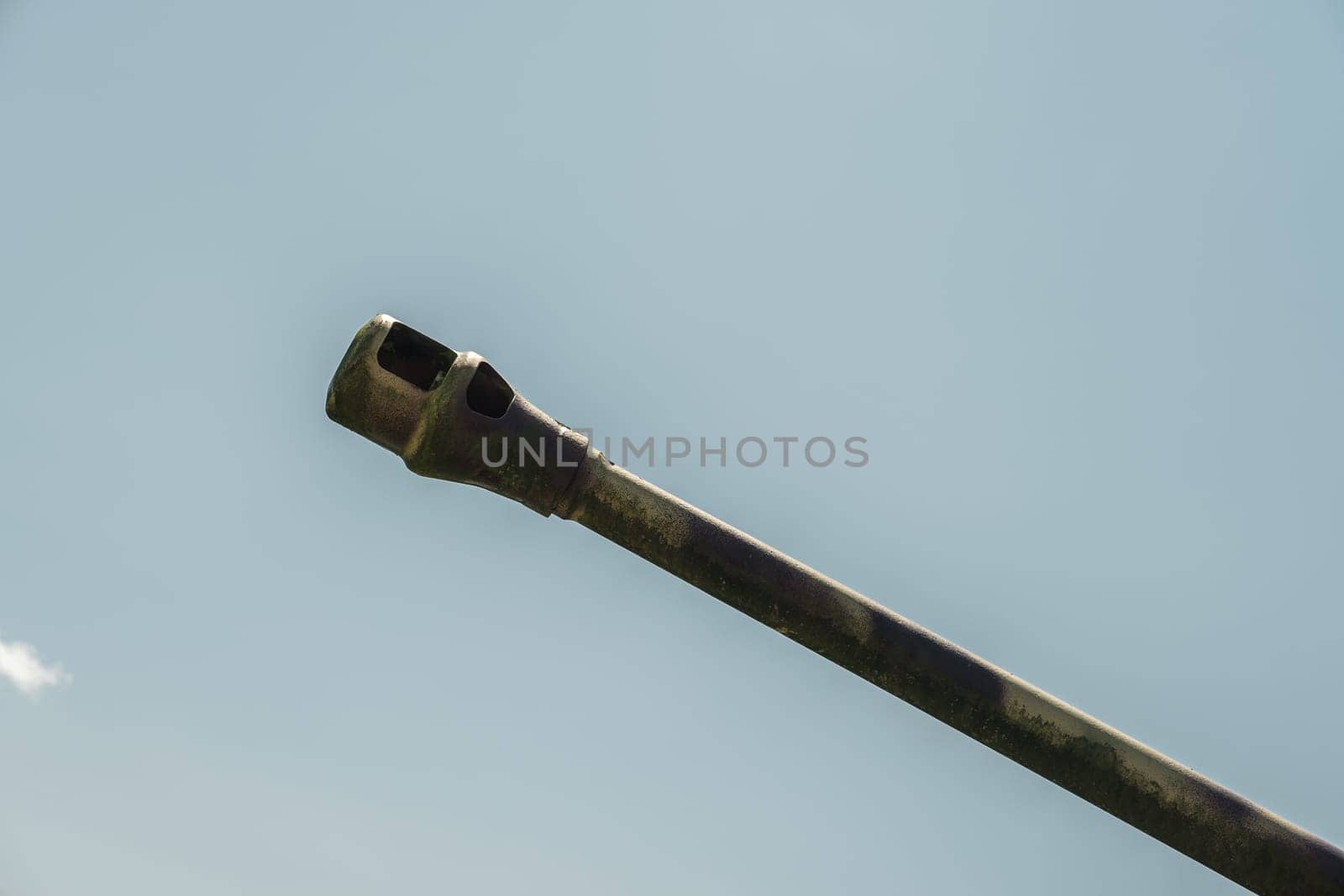 Tank gun barrel shot from below isolated against blue sky close up