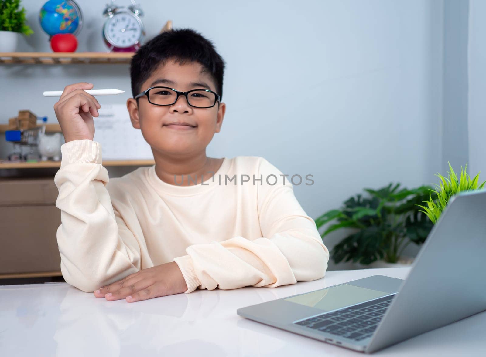 Little Asian boy student using computer laptop learning. Educational of tech concept, Staying at home, Presenting a modern educational way of life. Virtual internet online class from school teacher.