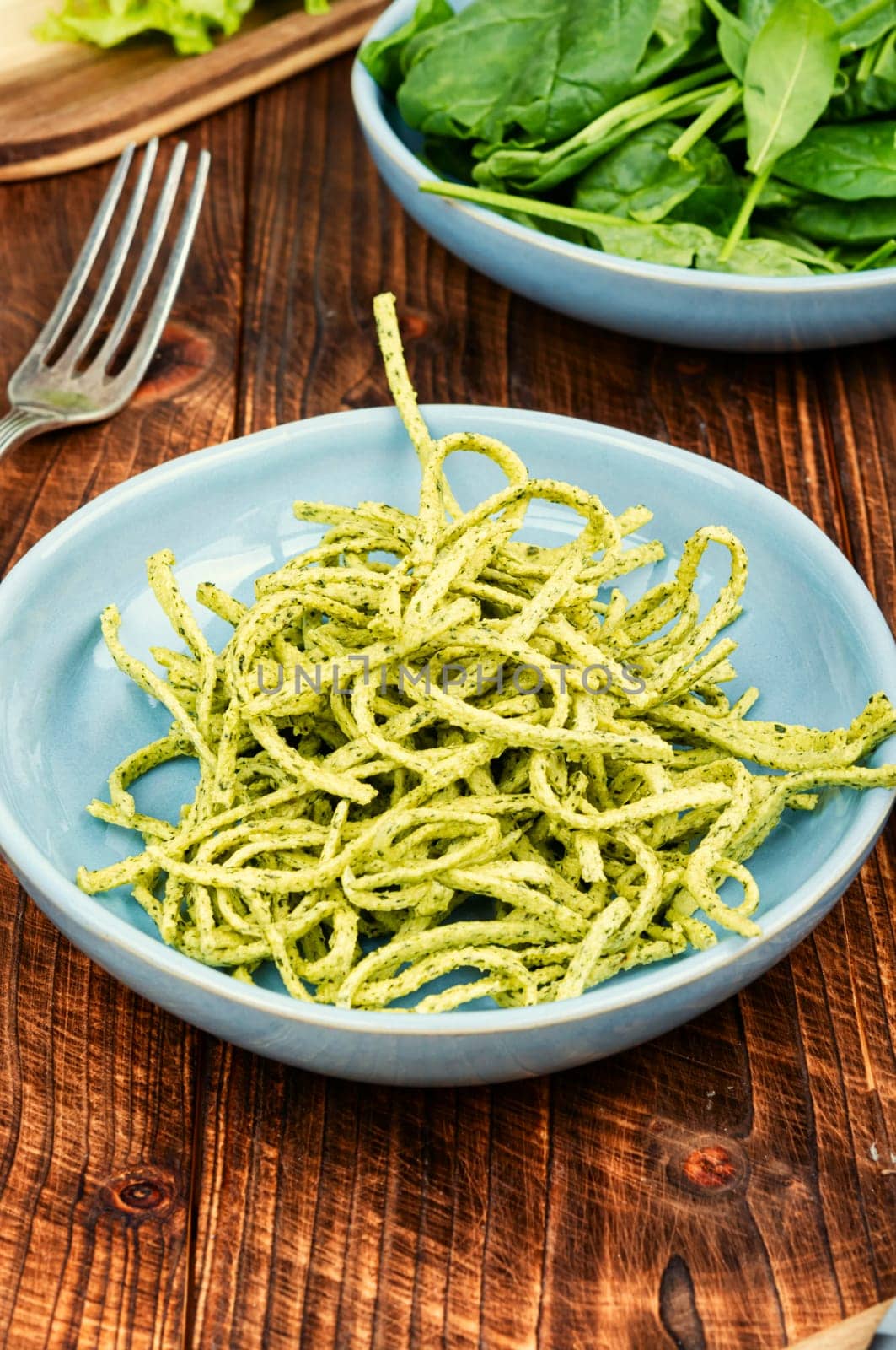 Vibrant green spinach or spinach pasta with fresh spinach leaves on wooden table. Culinary recepies, healthy food, fitness, diet.
