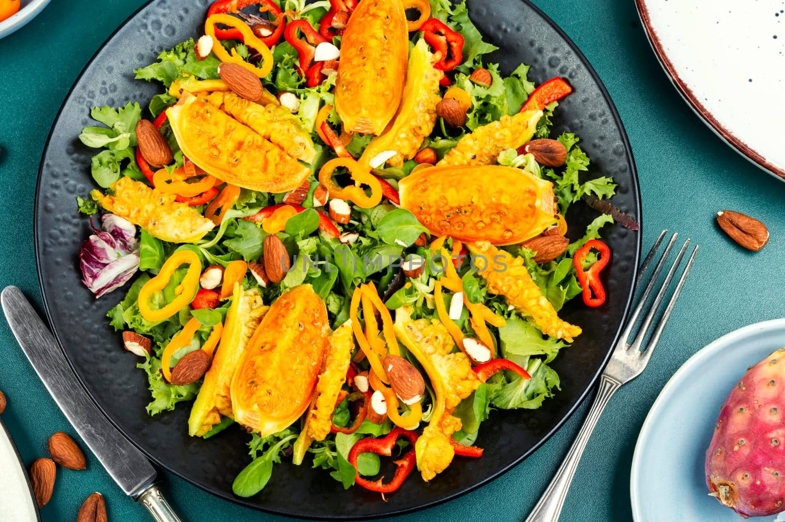 Cactus salad with sliced opuntia or prickly pear, peppers, almonds and fresh herbs, served in plate.