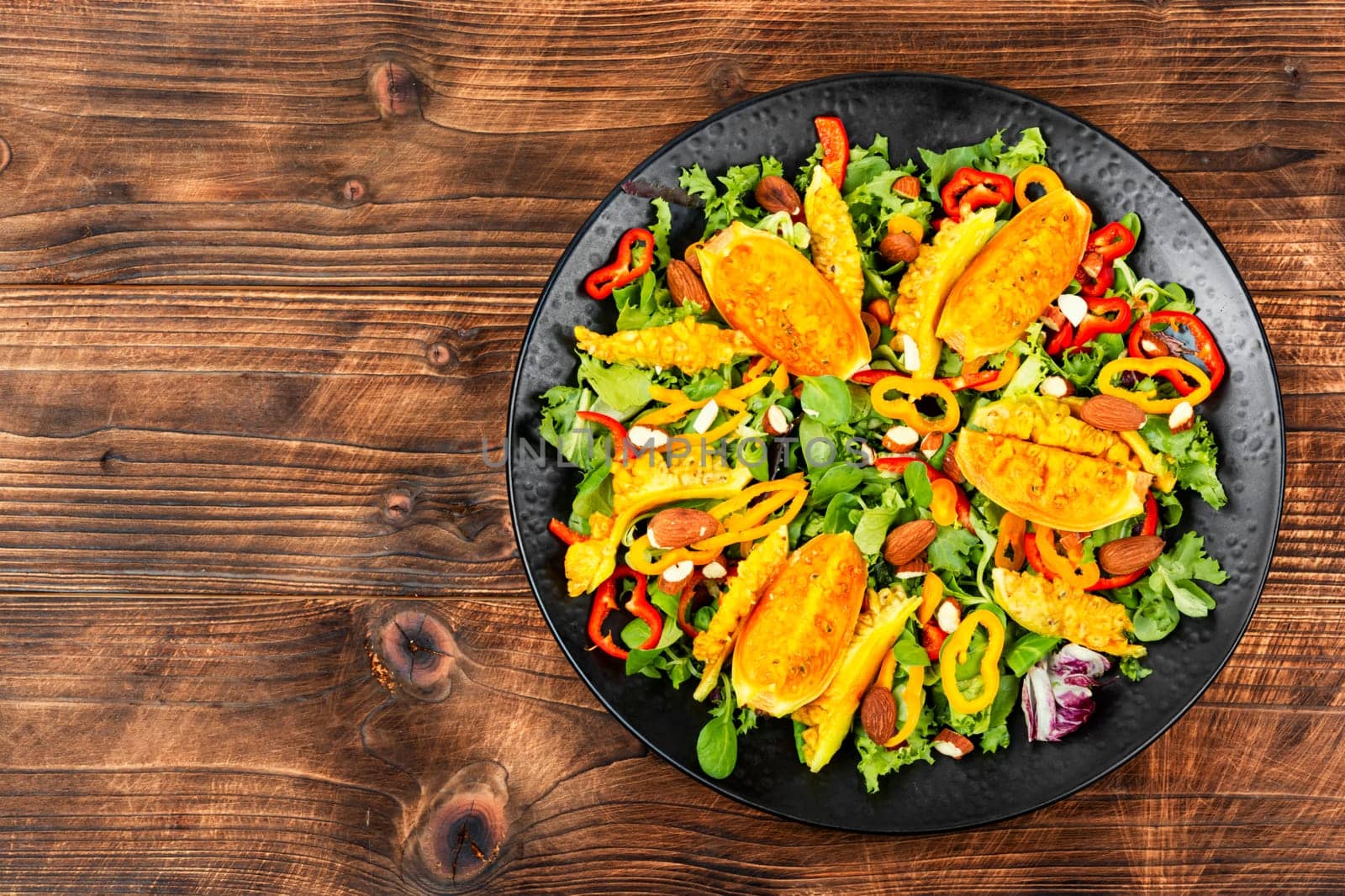 Colorful salad of prickly pear cactus fruits or cactus salad on rustic wooden table. Space for text.