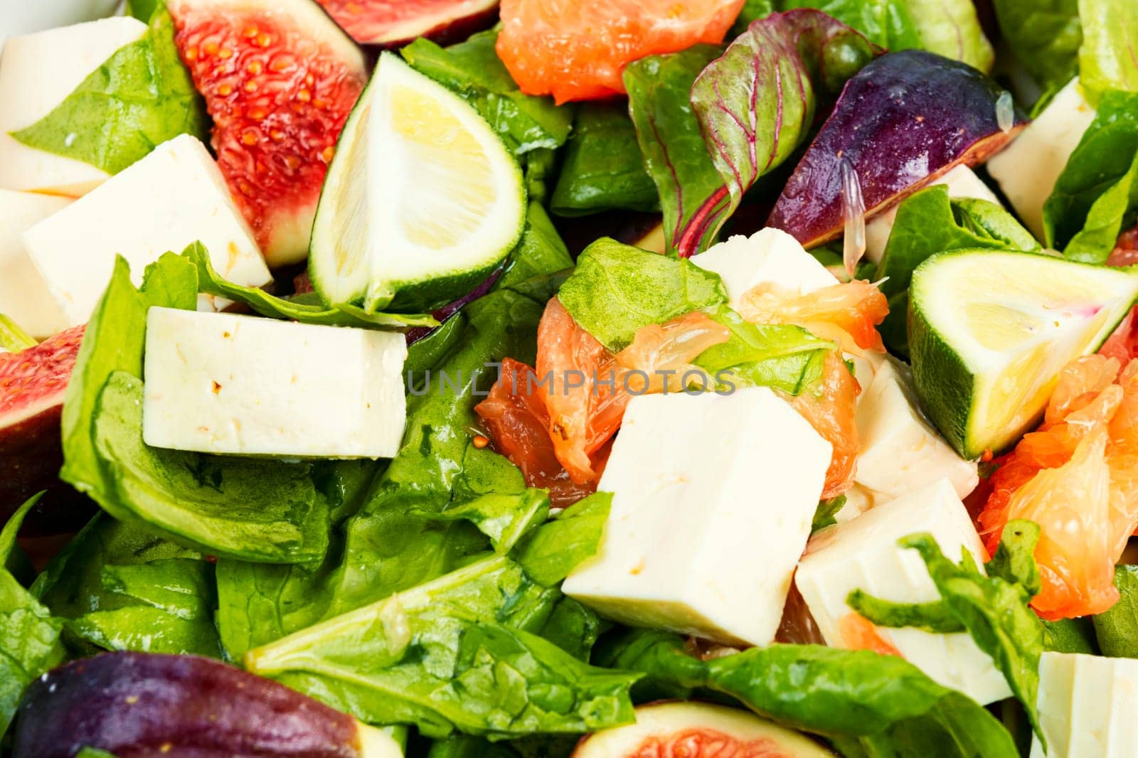 Vitamin salad with figs, greens and cheese. Close up.
