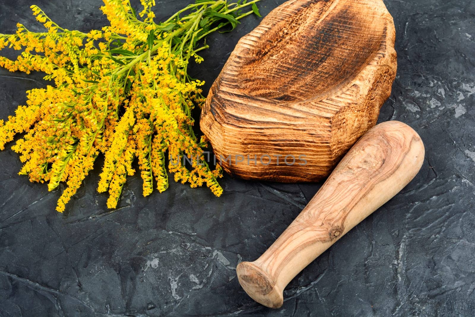 Medicinal herbs and vintage wooden mortar on a rustic wooden table.
