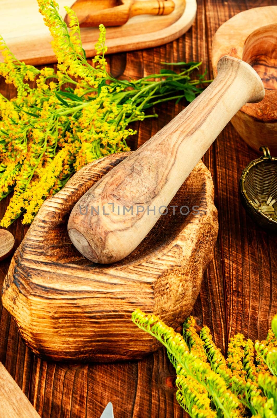 Medicinal herbs and vintage wooden mortar on a rustic wooden table.