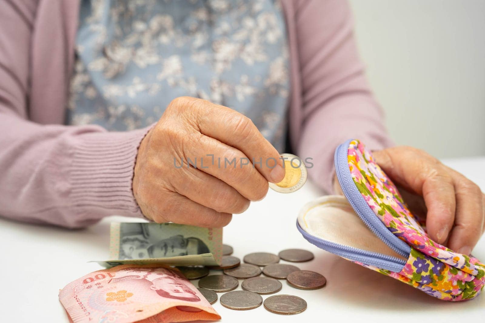 Asian senior or elderly old lady woman holding counting coin money in bag. Poverty, saving problem in retirement.
