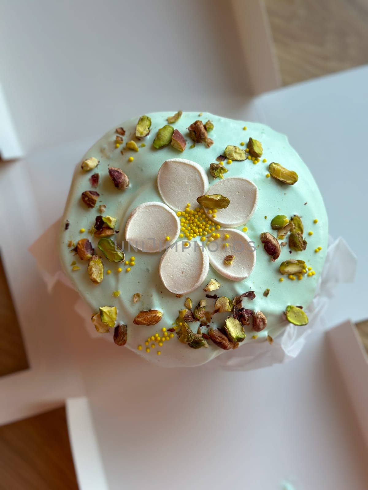 Beautifully decorated cake on a table, adorned with green icing and sprinkled with nuts and meringue pieces. Pastry is wrapped elegantly, perfect treat for special holidays. Sweet food and delicious vegan concept.