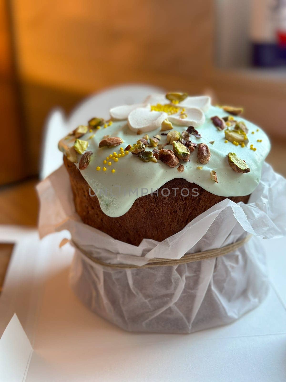 Beautifully decorated cake on a table, adorned with green icing and sprinkled with nuts and meringue pieces. Pastry is wrapped elegantly, perfect treat for special holidays. Sweet food and delicious vegan concept.