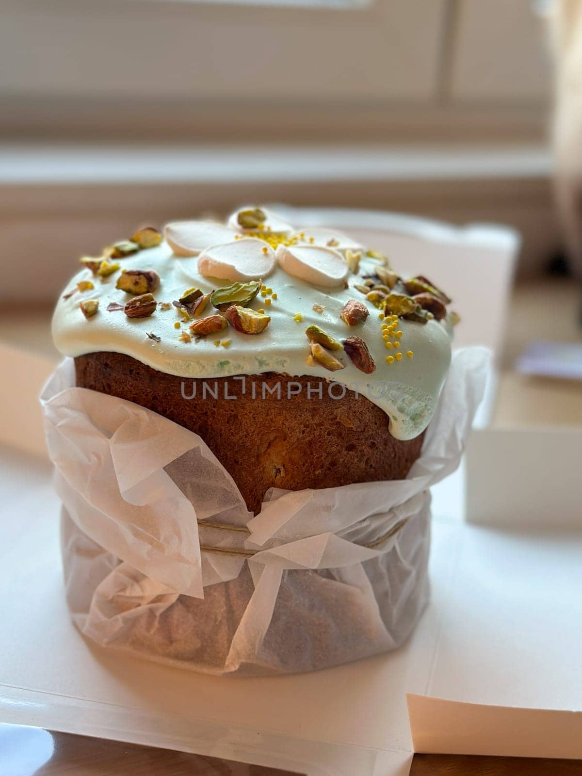 Beautifully decorated cake on a table, adorned with green icing and sprinkled with nuts and meringue pieces. Pastry is wrapped elegantly, perfect treat for special holidays. Sweet food and delicious vegan concept.