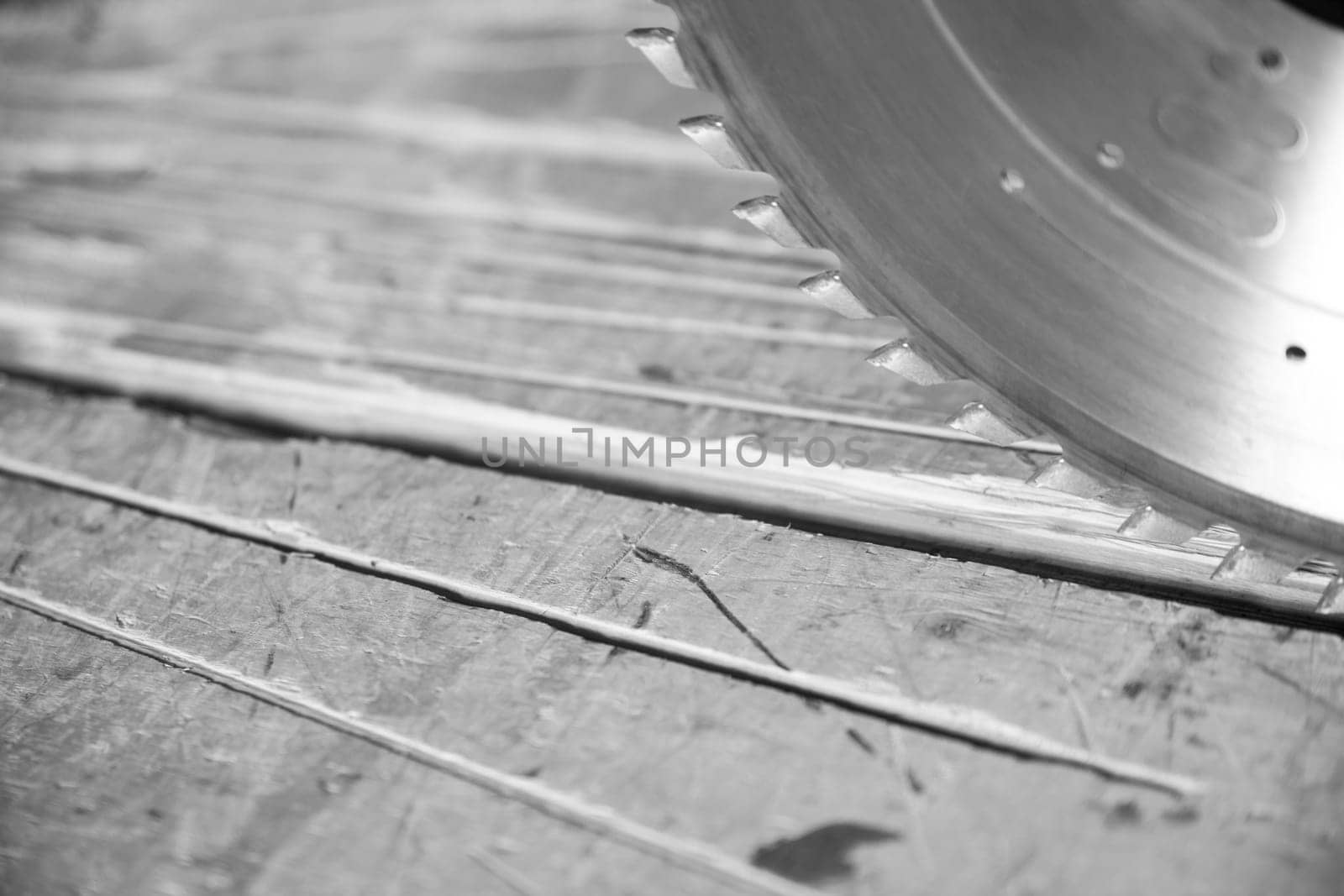 Circular saw cutting a wood plank in a carpentry workshop, with sawdust on the work surface. - black n white -