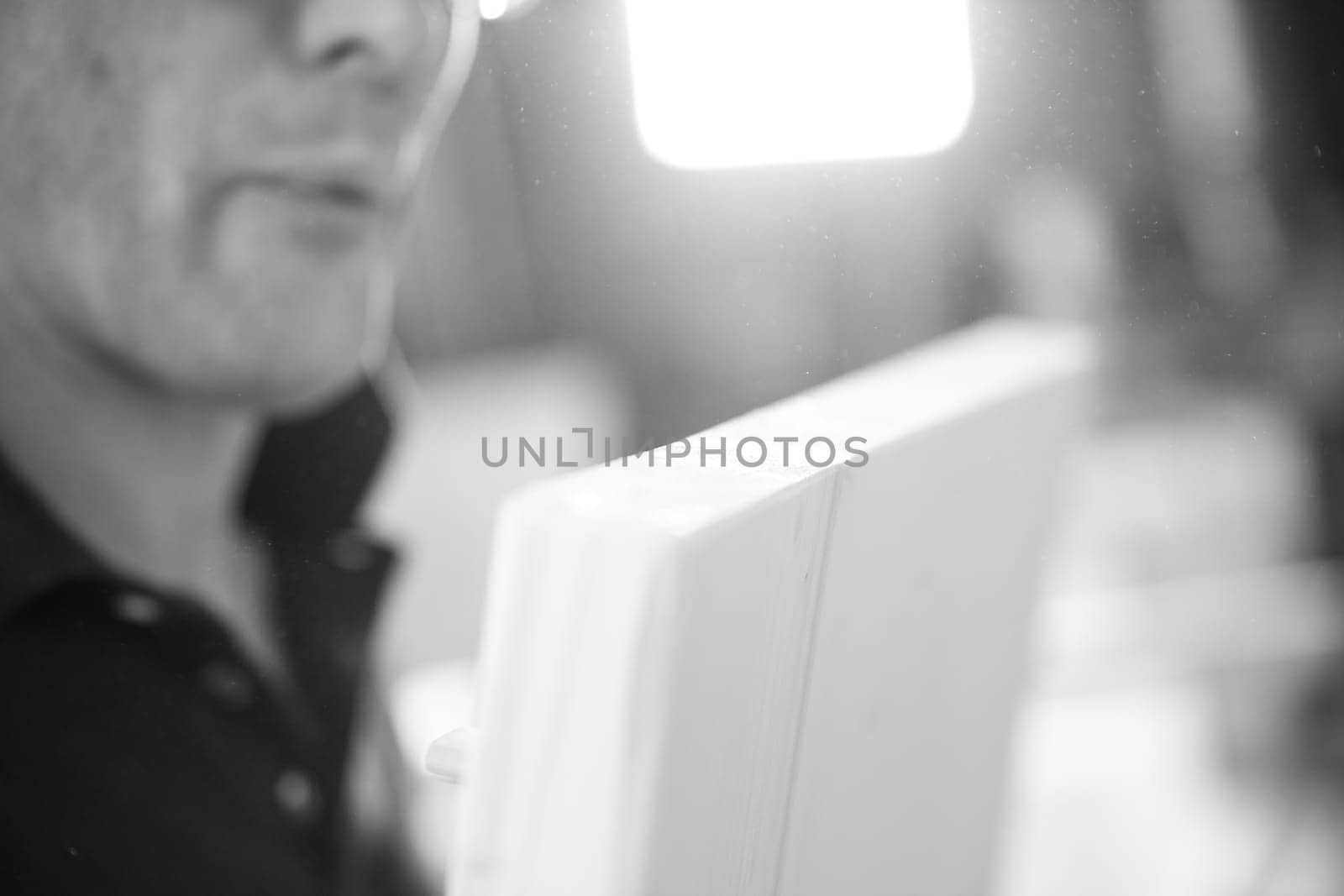 Close up of a carpenter blowing sawdust off a wood plank in a workshop, with strong hands and a determined expression. - black n white -