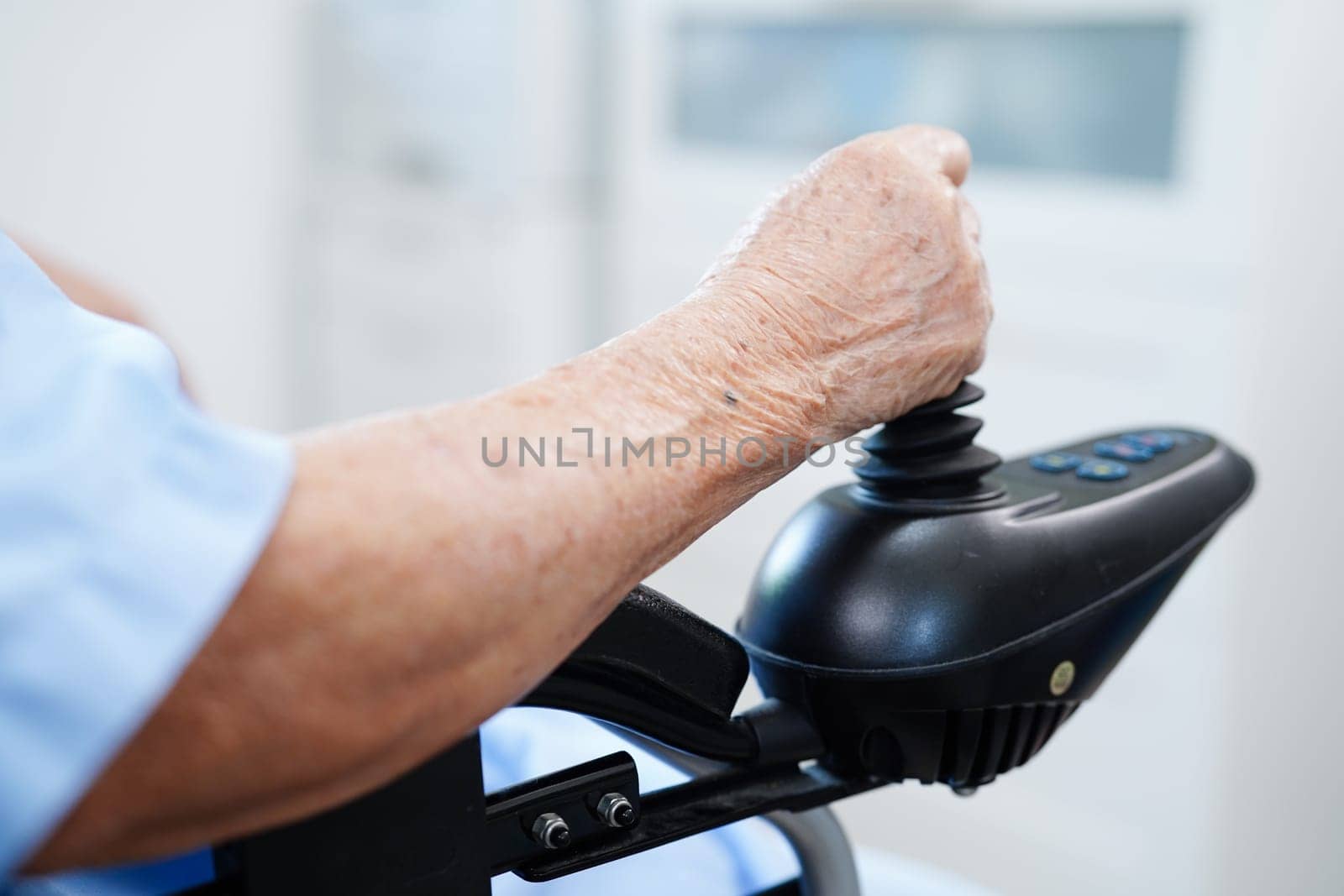 Asian elderly disability woman patient use joystick electric wheelchair in hospital.