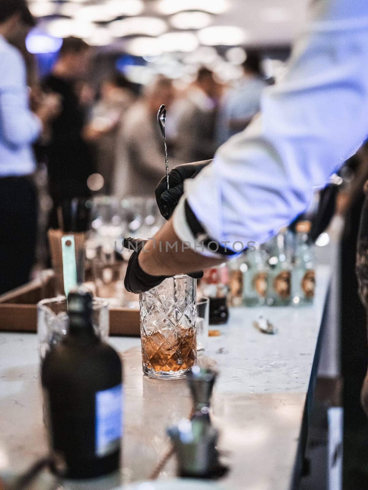 Expert barman is making cocktail at business banquet event in hotel conference center. Blurred businesspeople at banquet event business meeting event in the background.