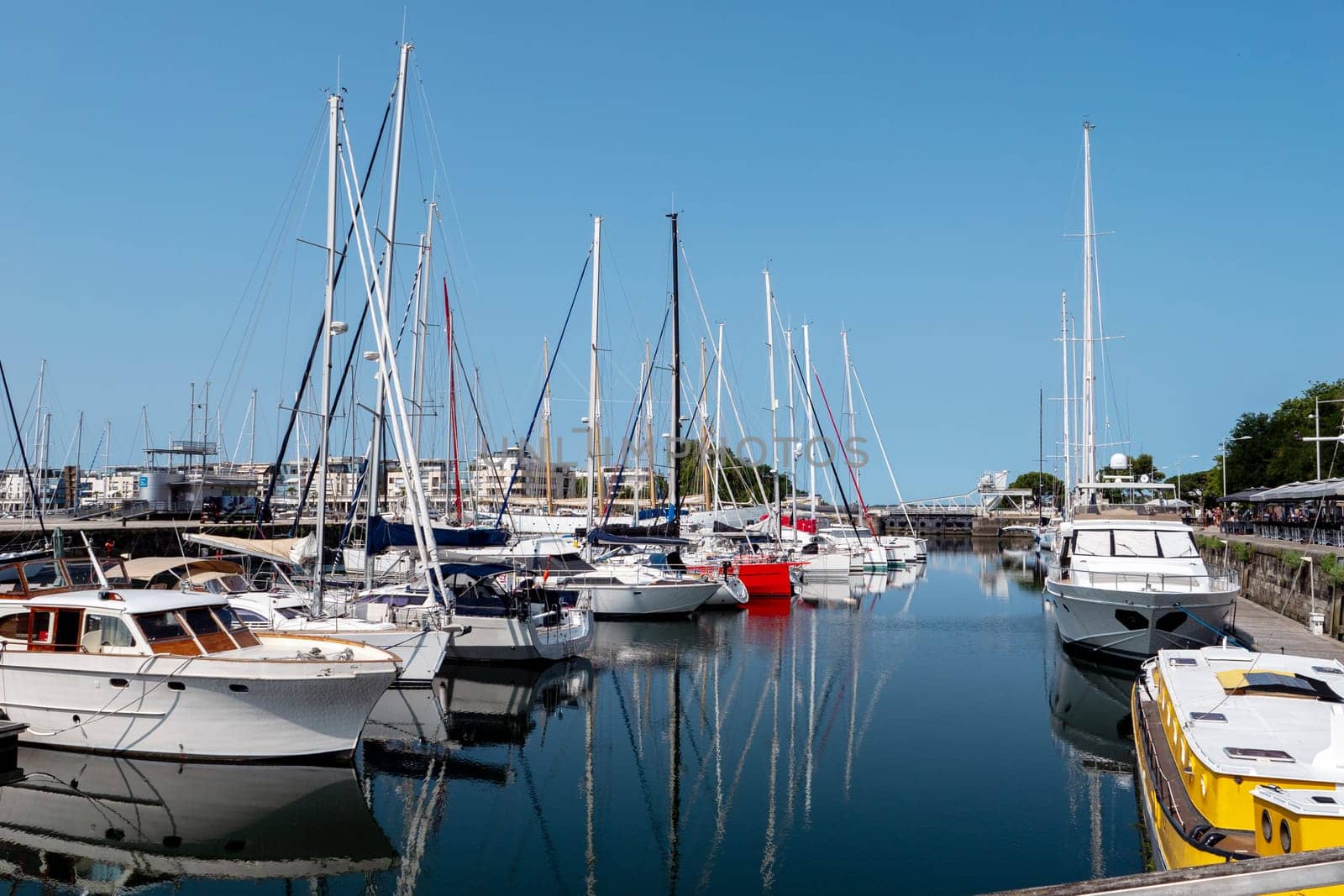 A large number of boats are docked at a marina. The boats are of various sizes and colors, including white, blue, red, and yellow. The scene is peaceful and serene