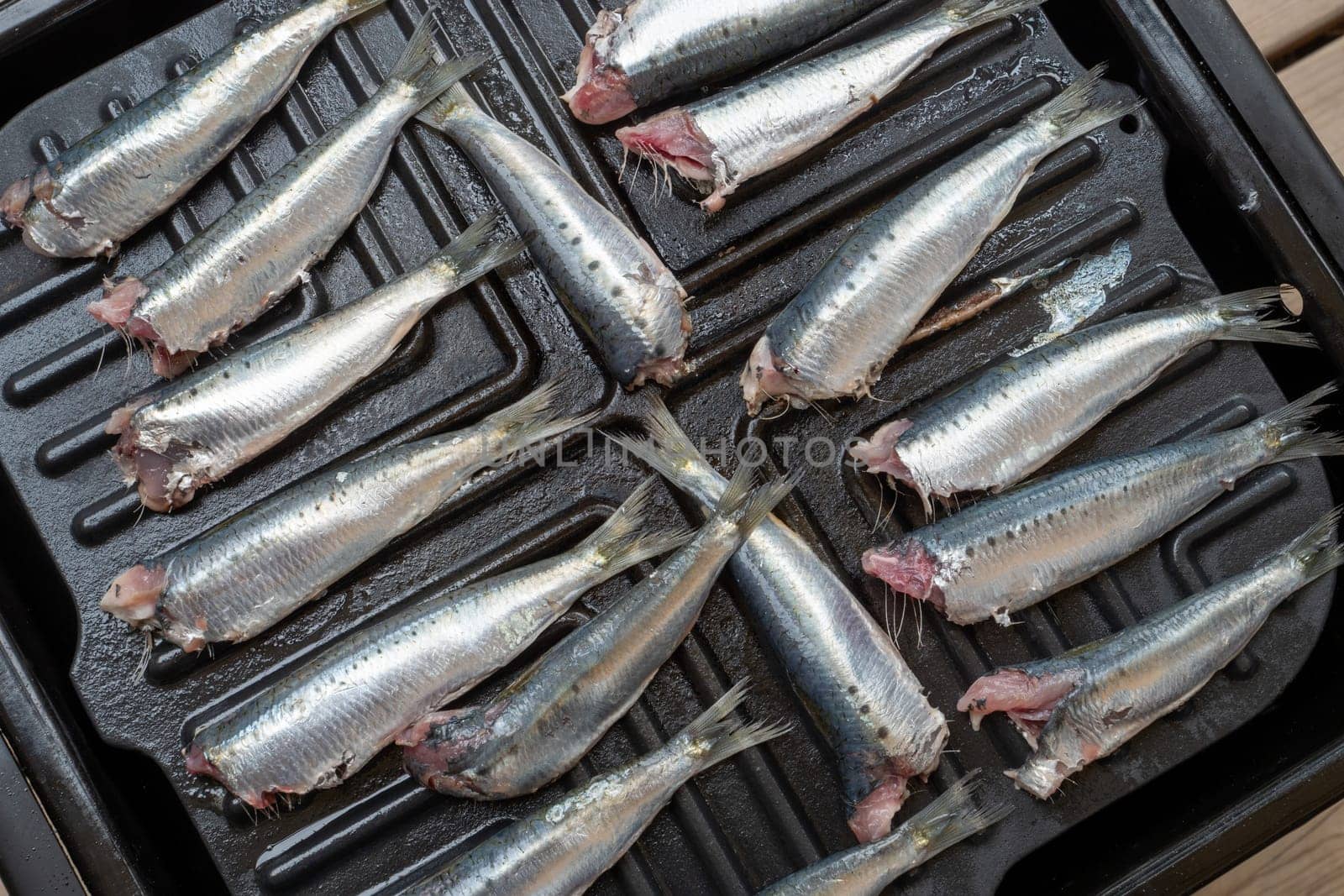 A pan of fish is on a grill. The fish are cut in half and are on the grill