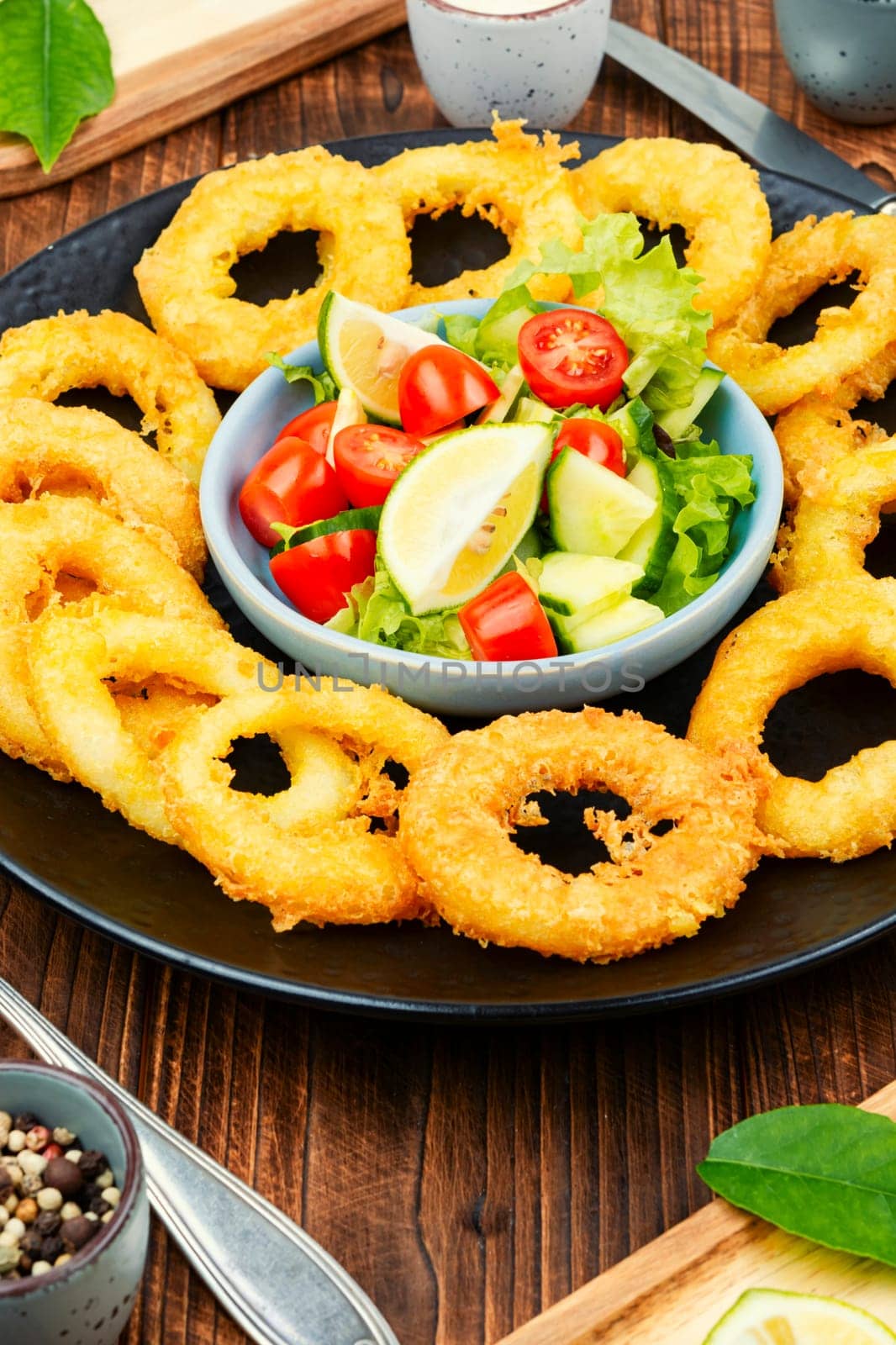 Delicious Fried squid rings and fresh vegetable salad on stone table background. Copy space.
