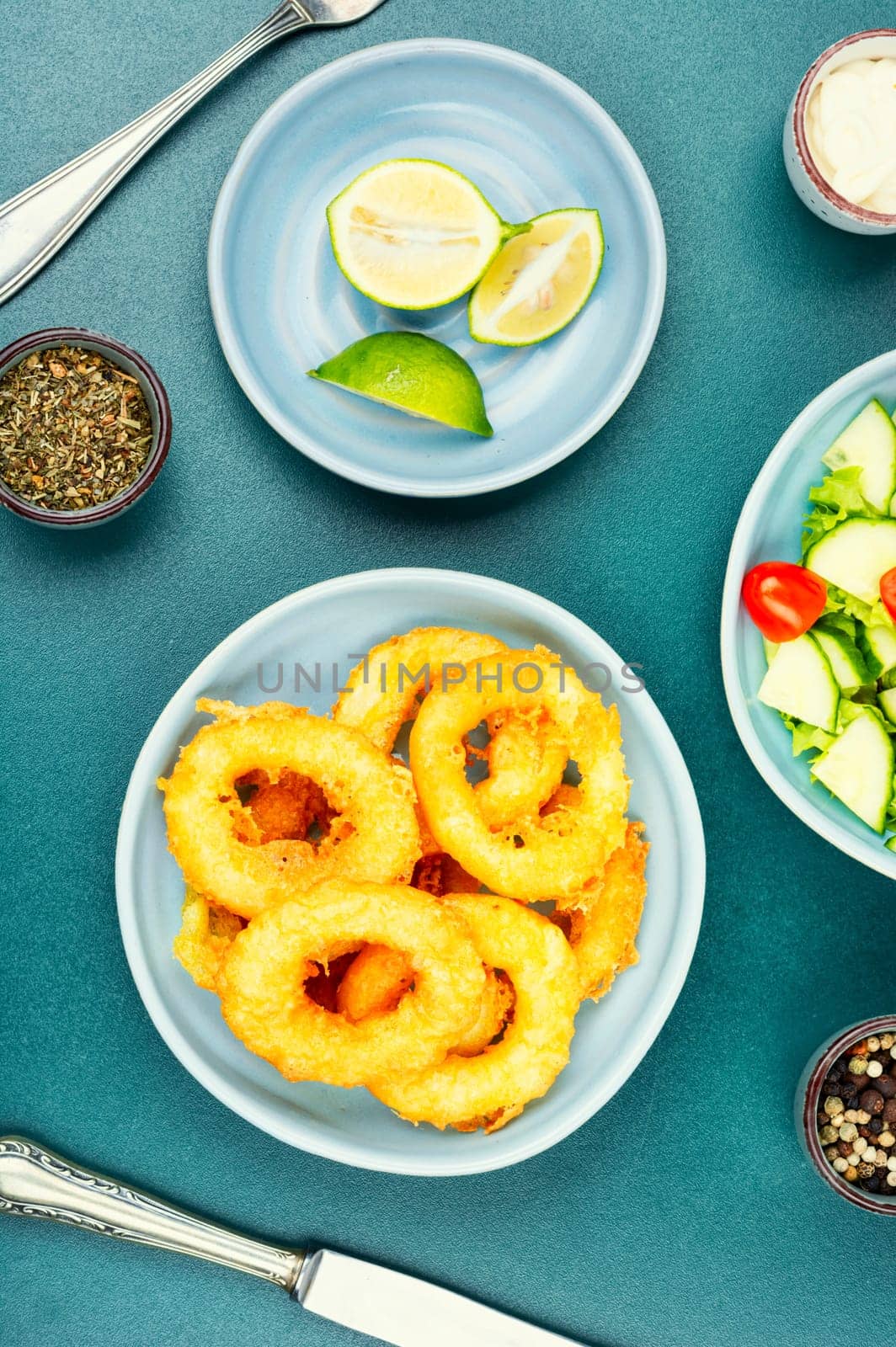 Delicious Fried squid rings and fresh vegetable salad on stone table background. Copy space.
