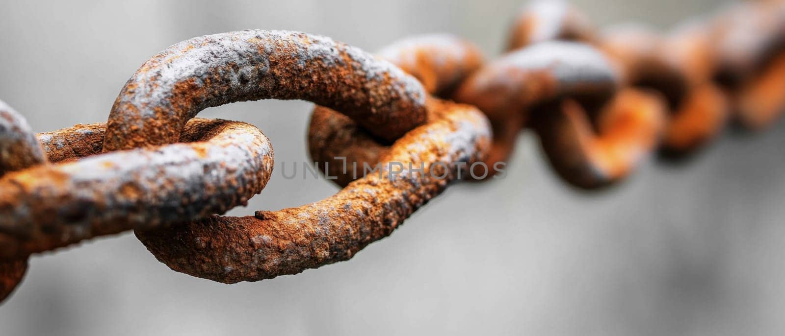 A close up view showcases a rusty chain interconnecting two aged surfaces demonstrating times impact on metal.