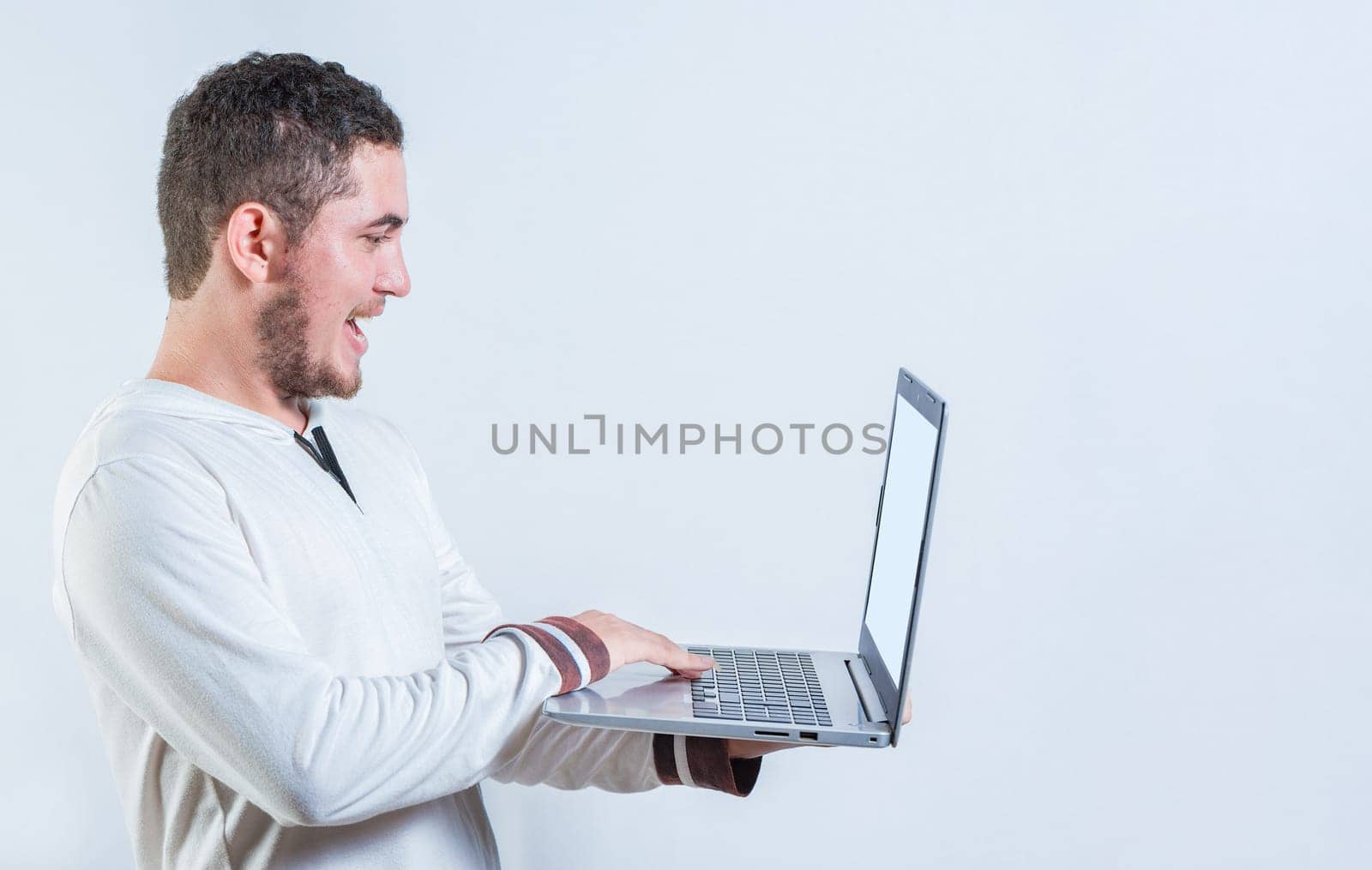 Portrait of happy young man standing using laptop isolated. Excited guy holding and looking at an promotion on laptop screen
