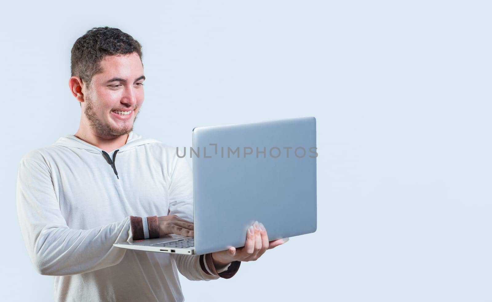 Excited guy holding and looking at an promotion on laptop screen. Portrait of happy young man standing using laptop isolated