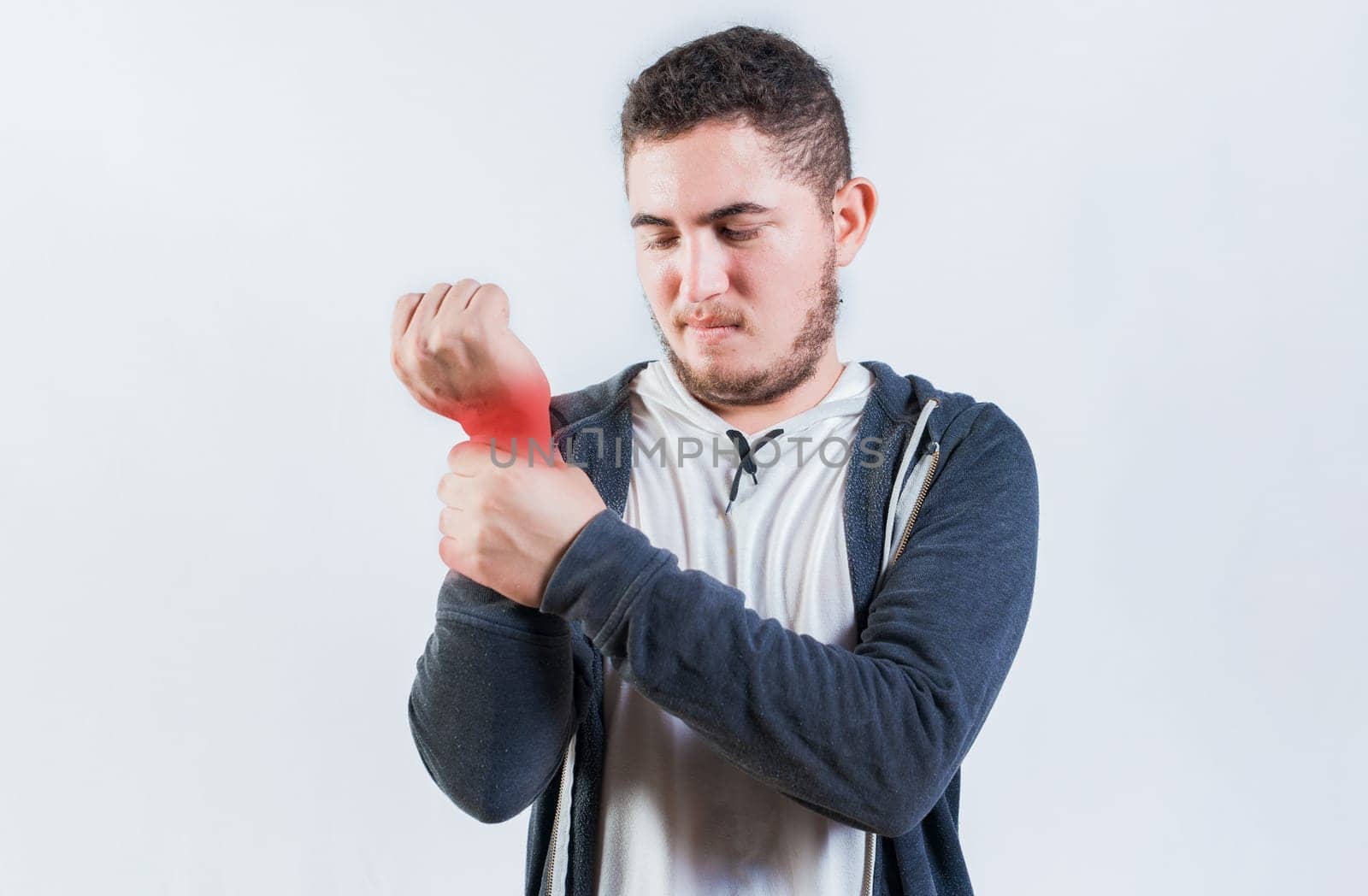 Suffering young man with pain in hand joints isolated. Person with arthritis pain rubbing hand
