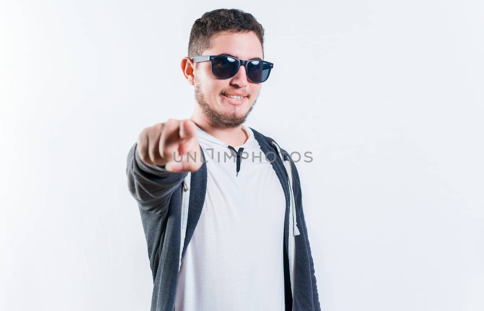 Handsome guy in sunglasses smiling and pointing at the camera isolated