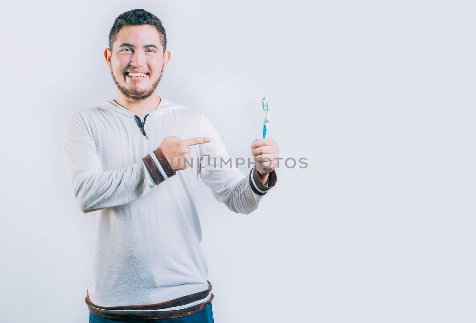Happy guy pointing at toothbrush isolated. Handsome man holding and pointing toothbrush isolated