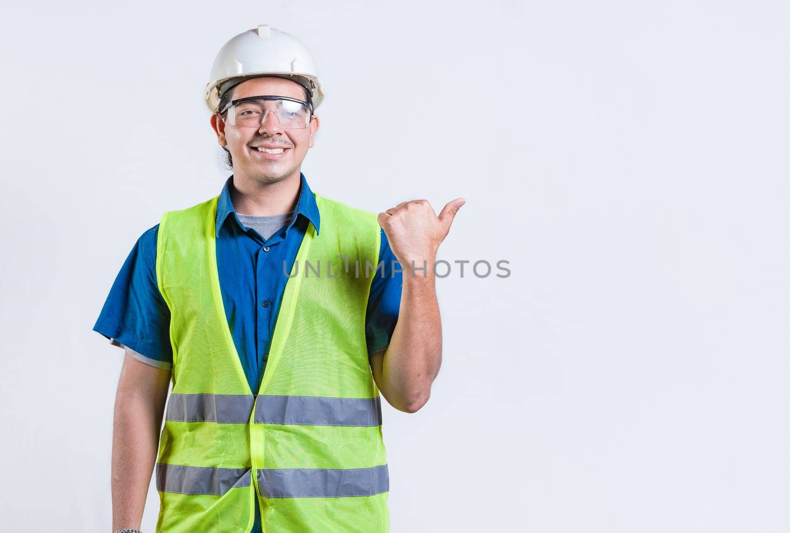 Portrait of engineer man pointing to side isolated. Smiling engineer man pointing side isolated