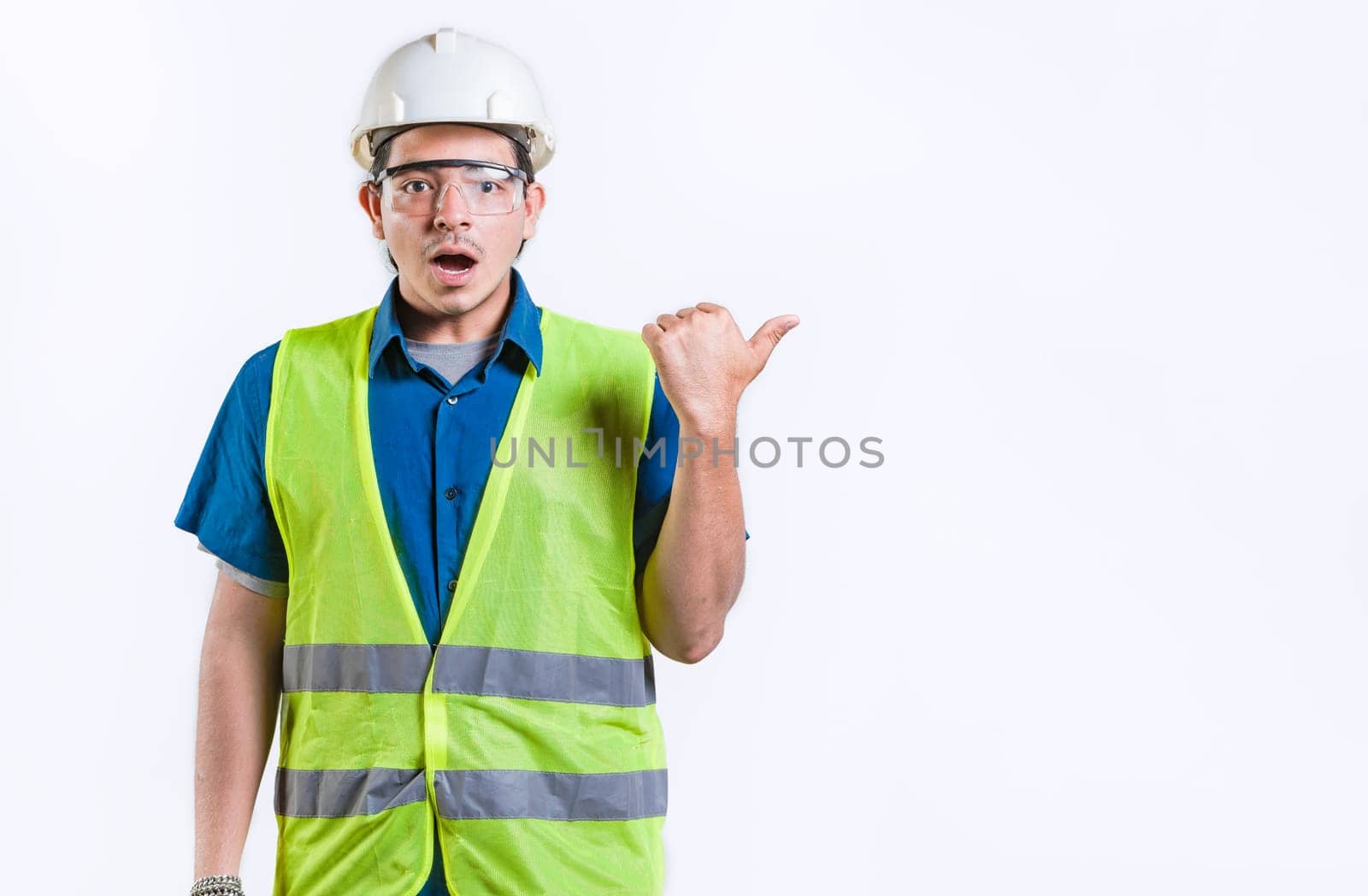 Surprised young engineer pointing side advertising space isolated. Amazed engineer pointing to the side an advertising space