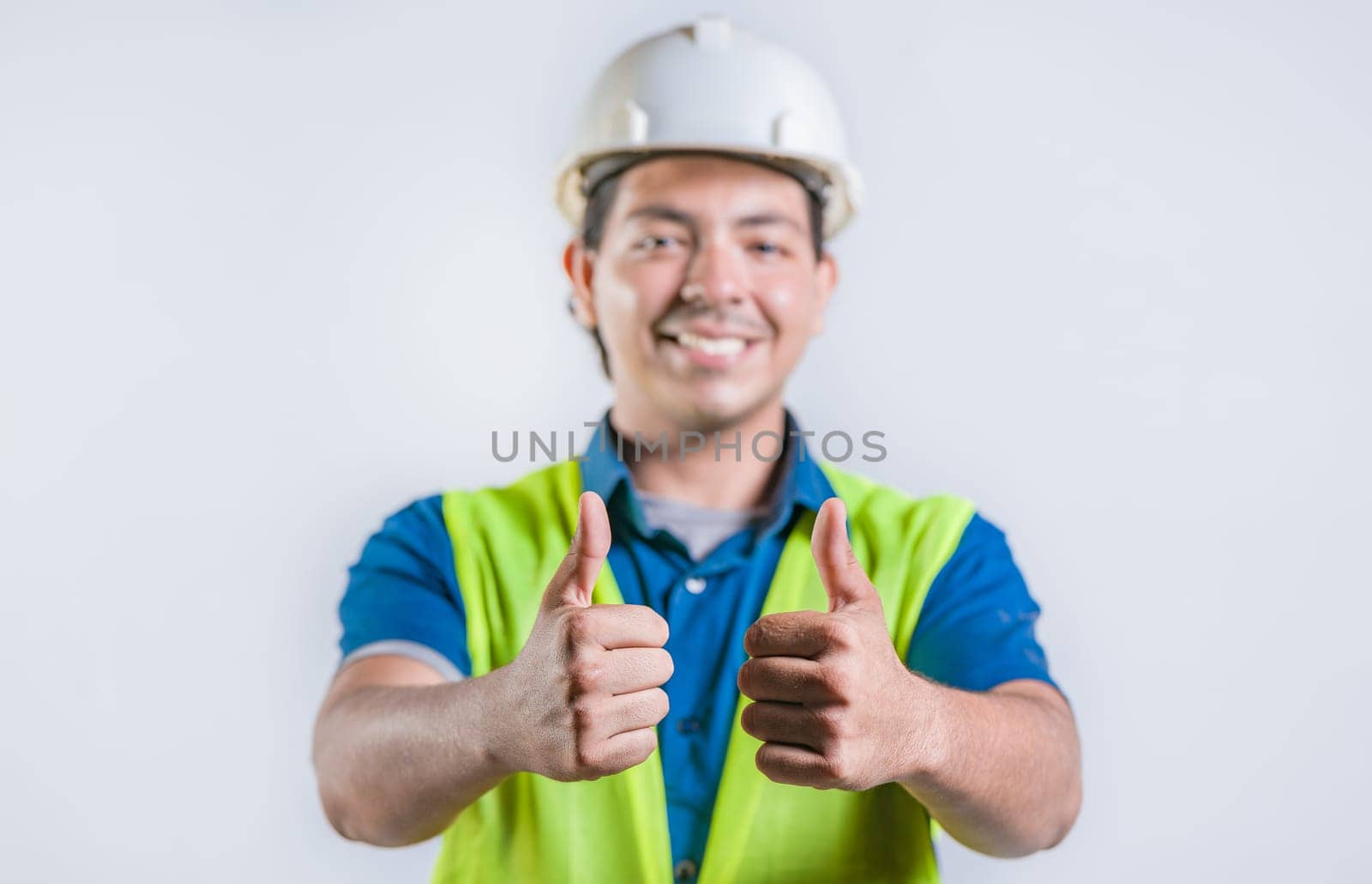 Smiling latin engineer geesturing ok isolated. Positive male engineer with thumbs up, isolated