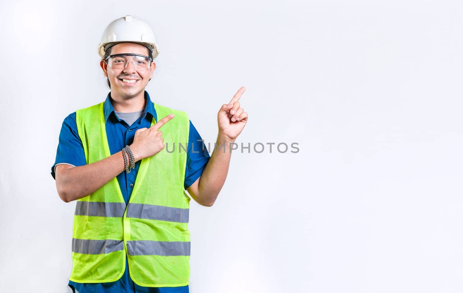 Happy male engineer pointing to side isolated. Smiling male engineer pointing blank space isolated
